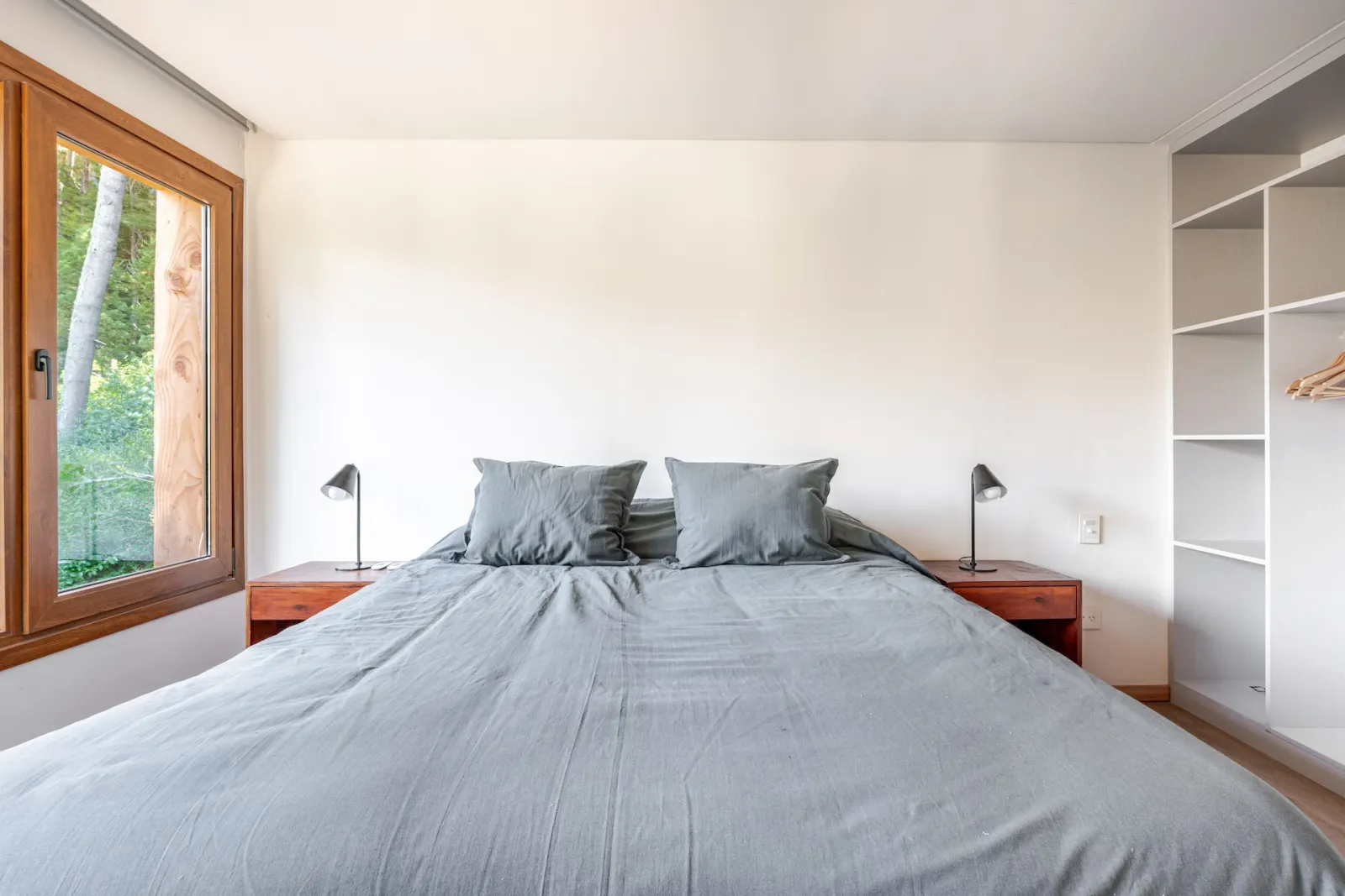 King bedroom with warm timber details and forest views