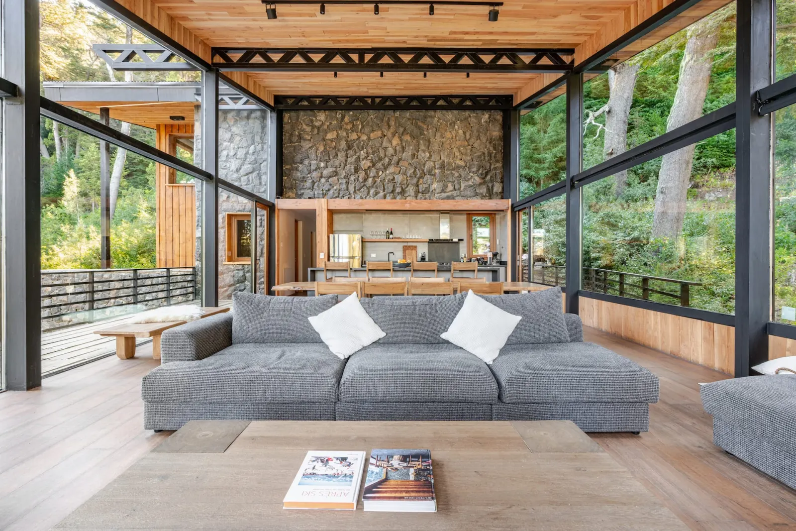 Glass-walled living and dining room surrounded by Patagonian forest