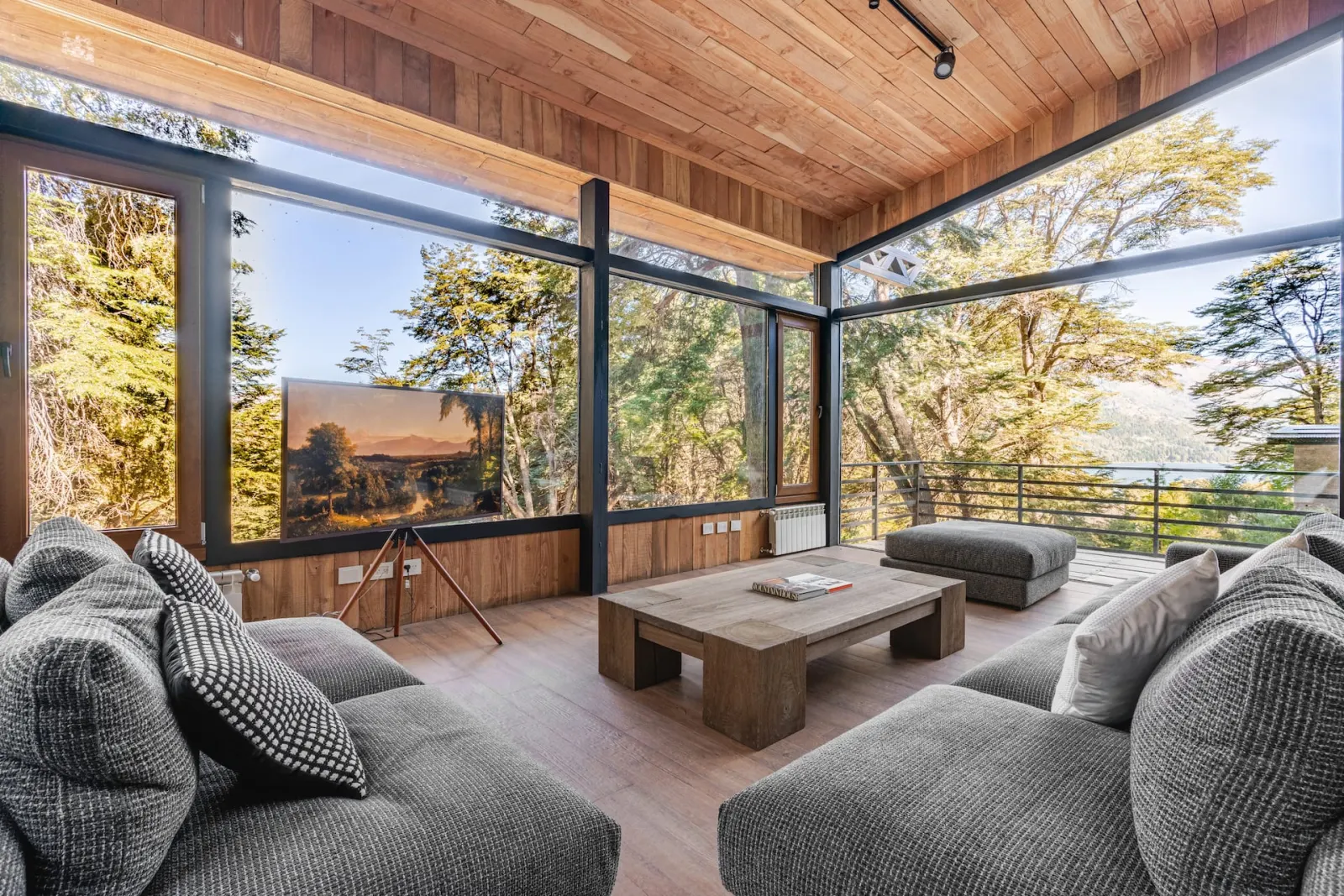 Glass living room with panoramic forest and lake views